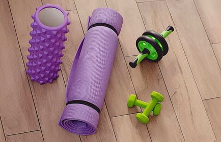 Christmas gifts for employees: a home workout kit including a foam roller, a rolled-up yoga mat, and a set of dumbbells