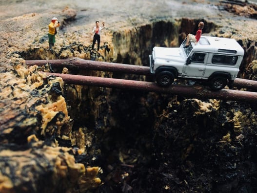 An image of figurines crossing a cavern while one rides on top of a car. While a good example of creatively solving a problem, OSHA may not view it as a quality of a good employee