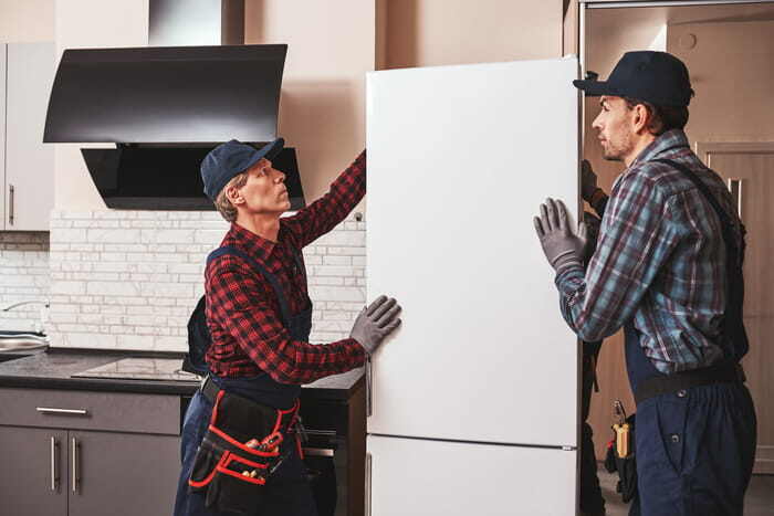 closing gifts for buyers option: Young men mechanics moving refrigerator