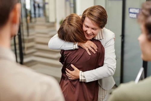Male and female employee hugging in appreciation, saying 'thank you, boss'