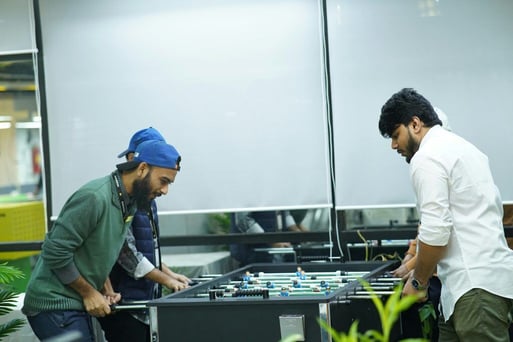 employees playing with a foosball table