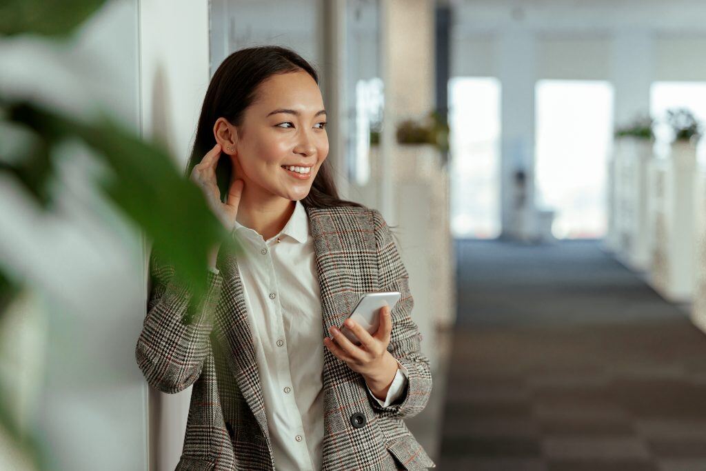 Asian female using a phone in an office, showcasing positive feedback examples