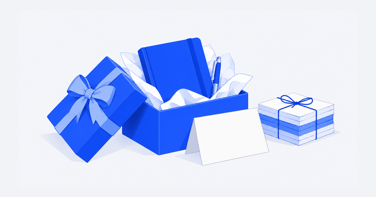 A blue notebook and pen in a gift box beside a blank card and a tied stack of wrapped gifts